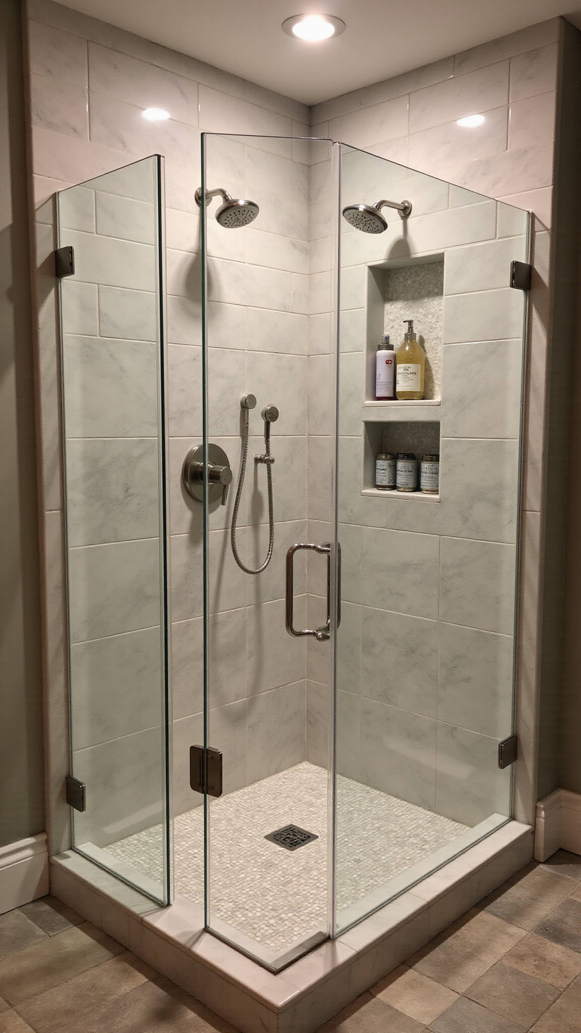 Luxury twilight bathroom with frameless glass shower, marble subway tiles, mosaic floor, and polished nickel fixtures.