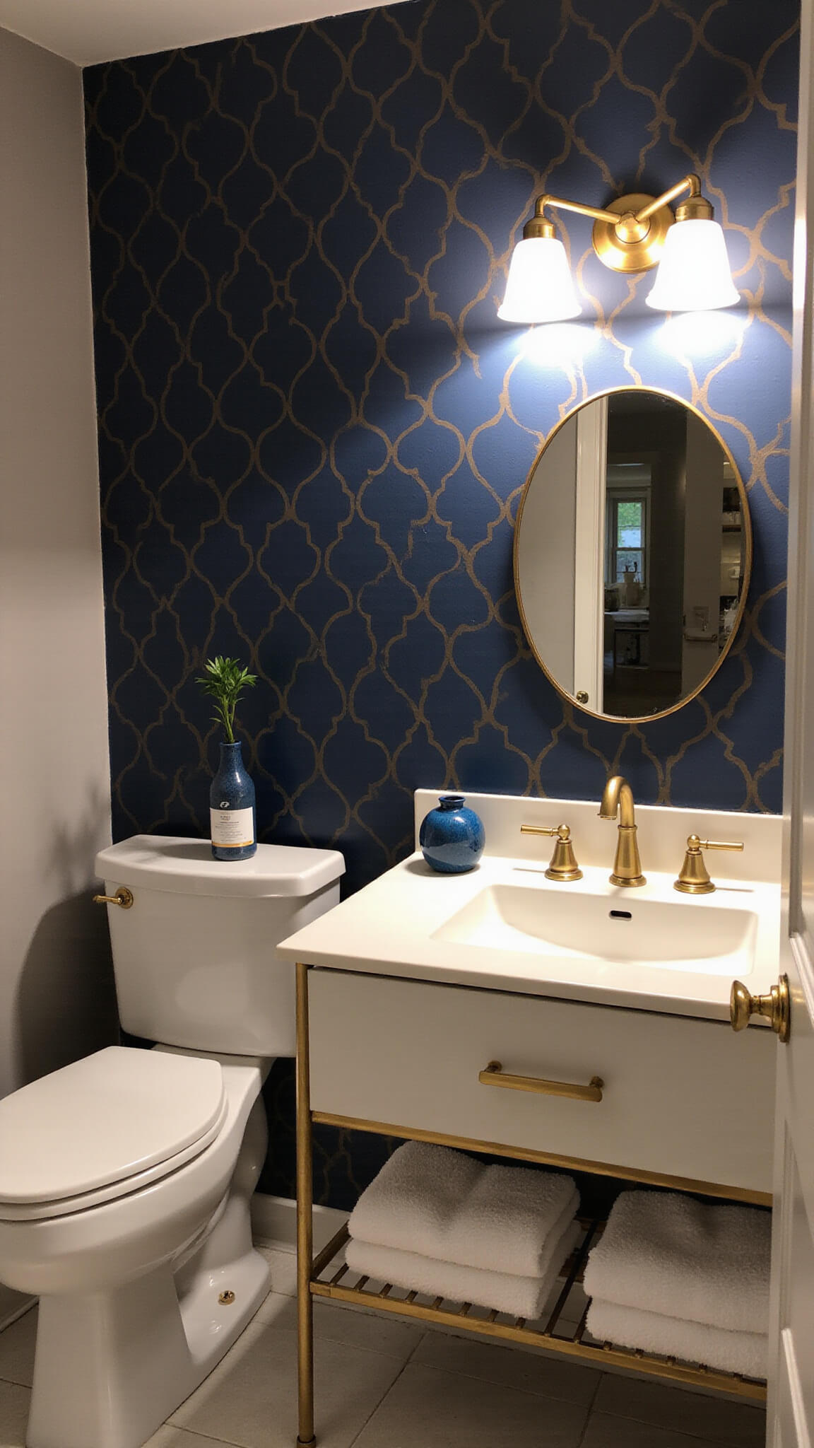 Modern navy and gold powder room at golden hour with geometric wallpaper, brass sconce, floating white vanity, gold accents, and minimalist decor.