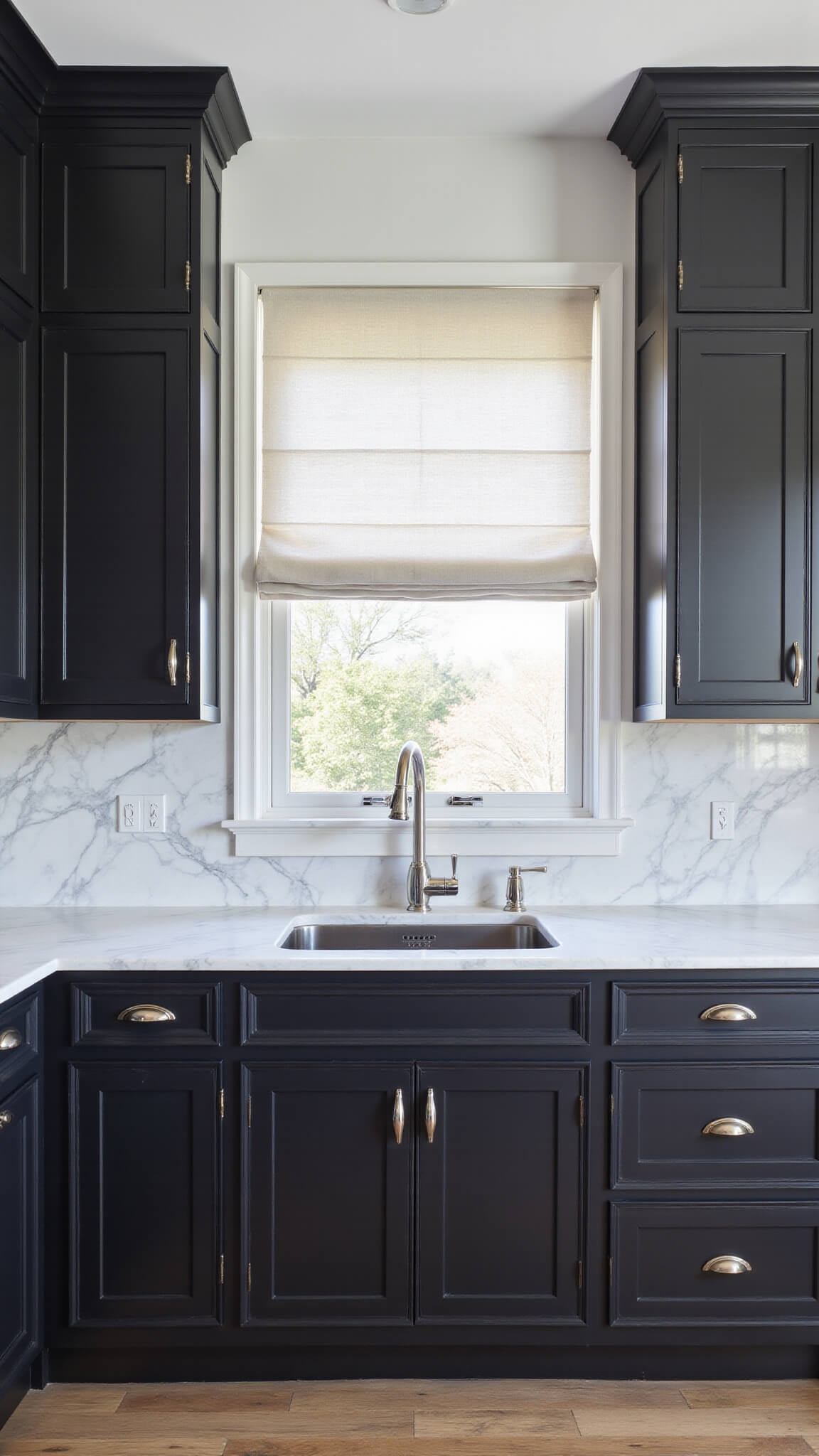 Contemporary 14x16ft kitchen with black floor-to-ceiling cabinets, white marble backsplash, polished nickel accents, and filtered afternoon light through white linen Roman shade.