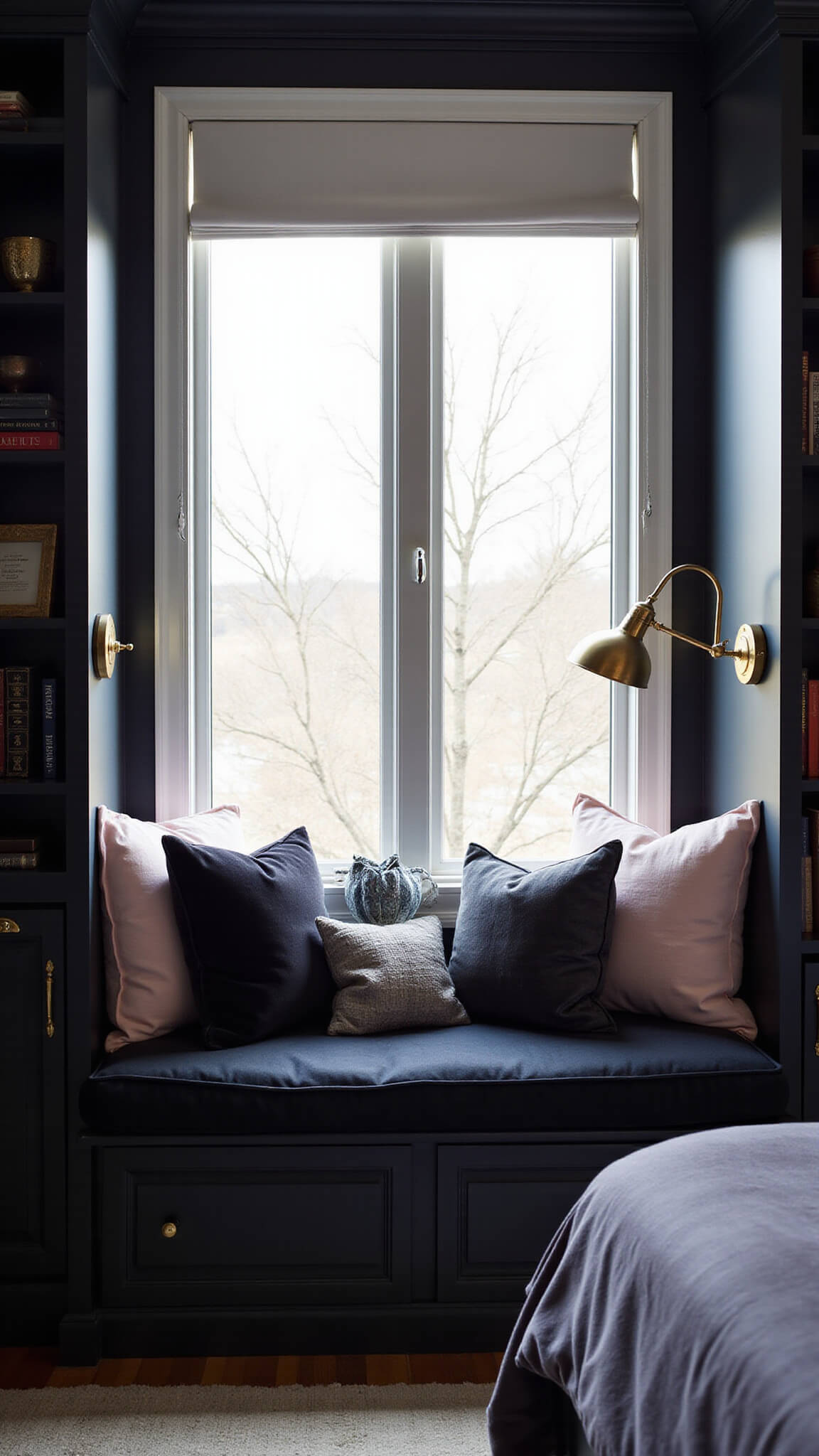 Cozy black bedroom reading nook with bay window, velvet cushions, brass sconces, layered pillows, built-in black bookshelves, and morning light.