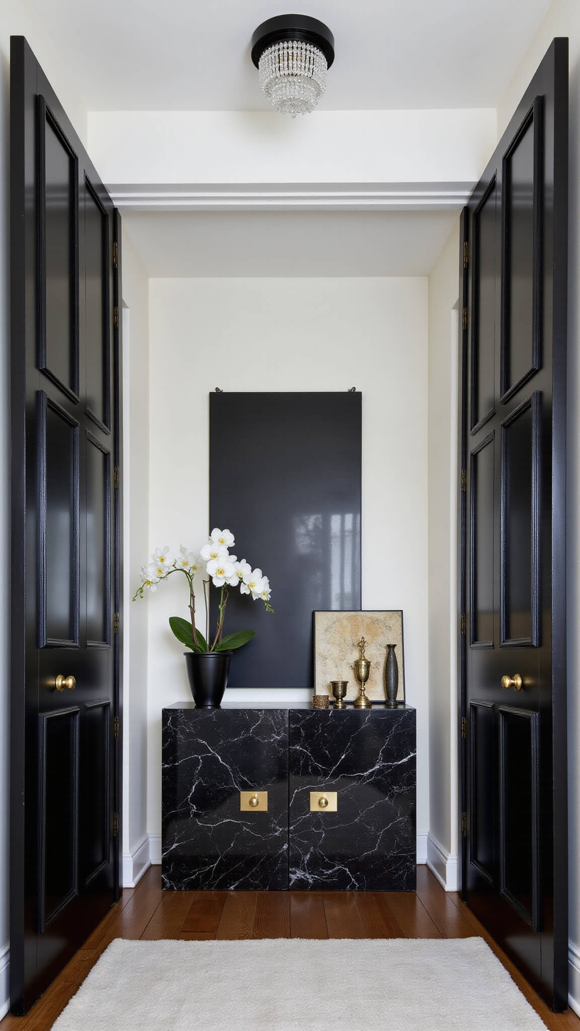 Contemporary black bedroom entrance with 9-foot black double doors, black marble console table, oversized mirror reflecting crystal ceiling light, and abstract black-and-white wall art.