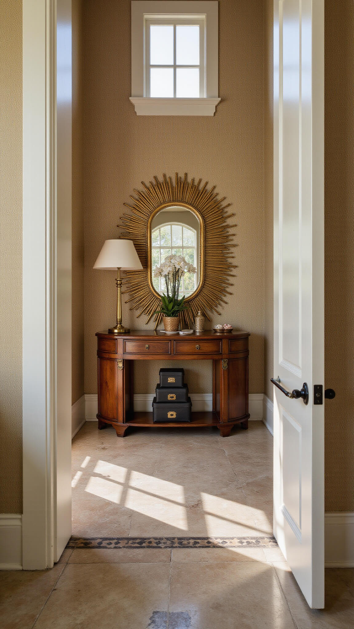 Art Deco walnut console table with brass accents beneath sunburst mirror, vintage hat boxes stacked below, set against grasscloth wallpaper and marble floor with geometric inlay, dramatic midday lighting.