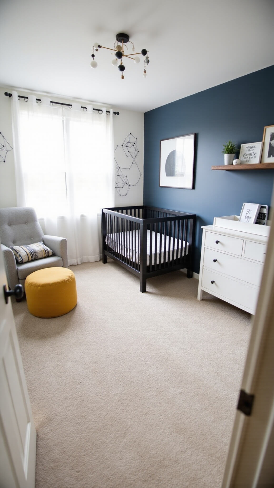 High-angle view of a modern minimalist nursery with matte black crib, navy accent wall with floating shelves, gray glider, mustard yellow pouf, and white dresser in natural daylight.