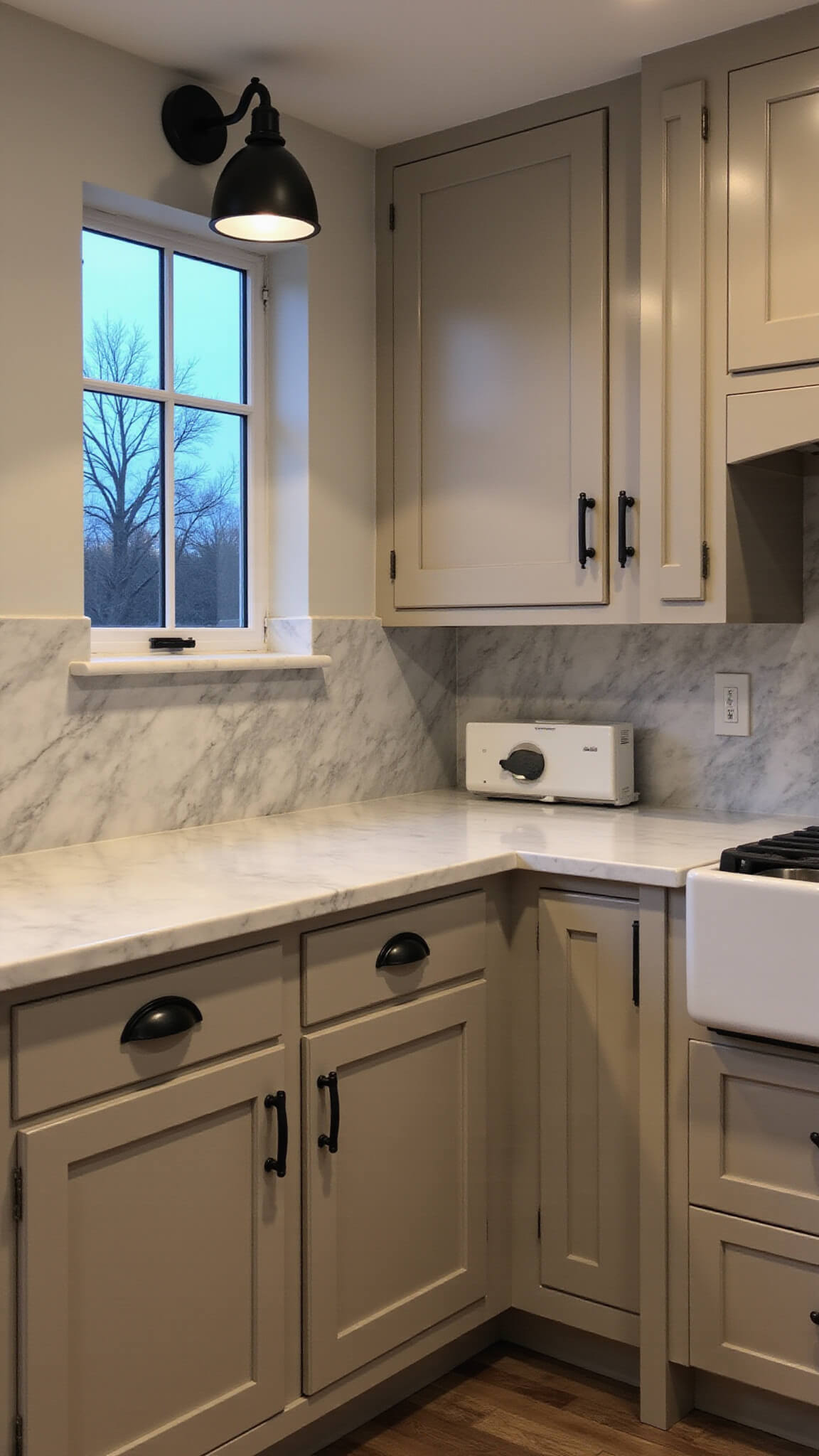 Modern farmhouse kitchen with beige Shaker cabinets, black iron fixtures, and marble slab backsplash at twilight.