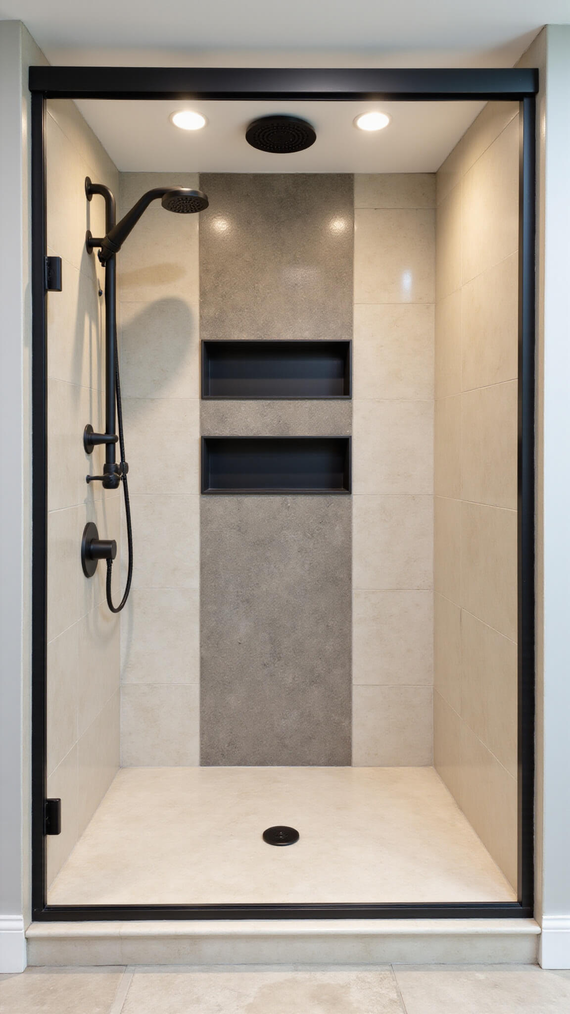 Modern alcove shower with cream marble-look tiles, matte black hardware, and three black recessed niches, evenly lit with LED lighting.