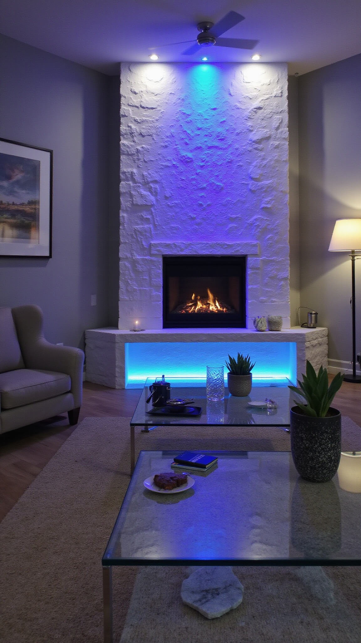 Evening view of modern great room with LED fireplace displaying rotating blue and purple lights against white stone, gray monochromatic furniture, and Lucite accents reflecting color.