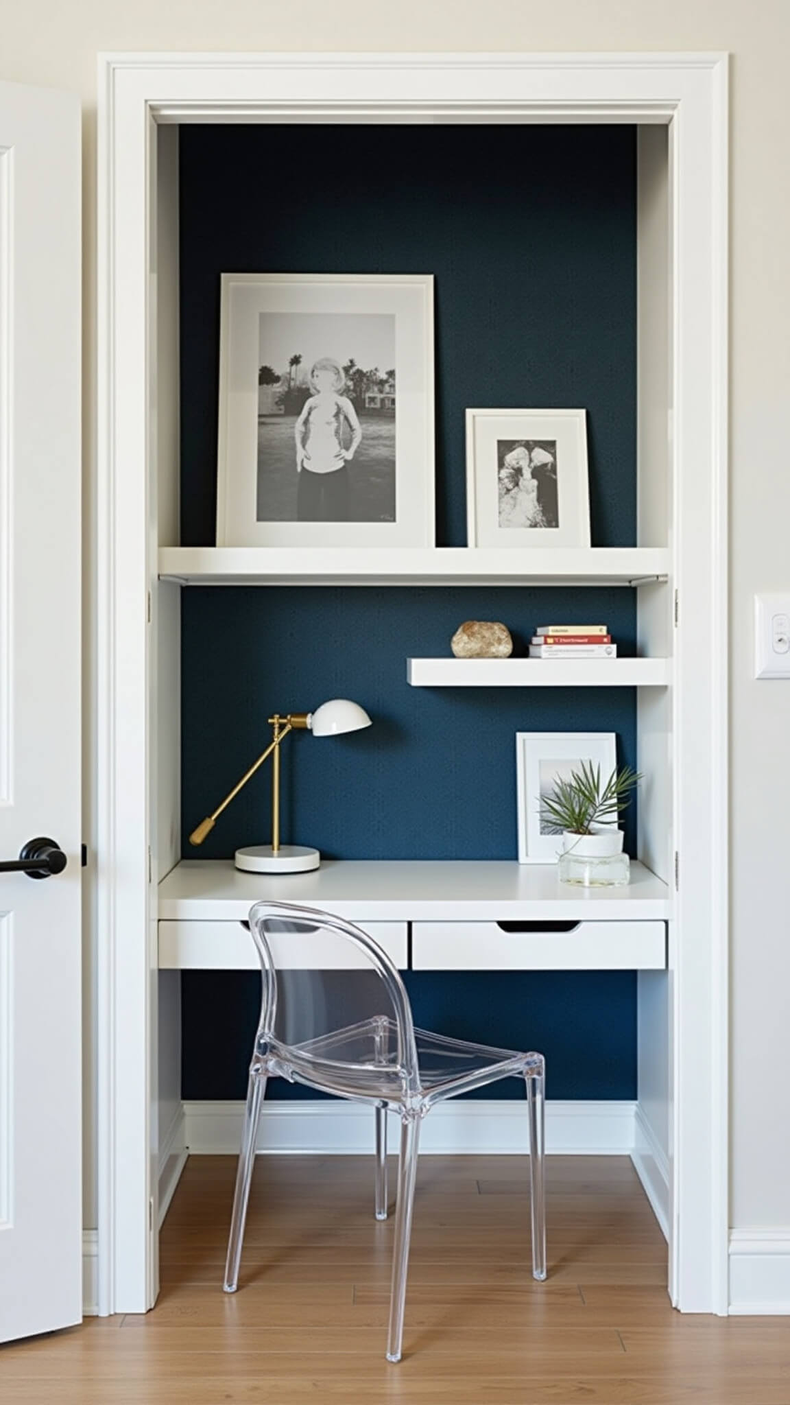 Modern alcove office with Murphy desk, ghost chair, floating shelves, and tech-minimal setup against navy wallpaper.