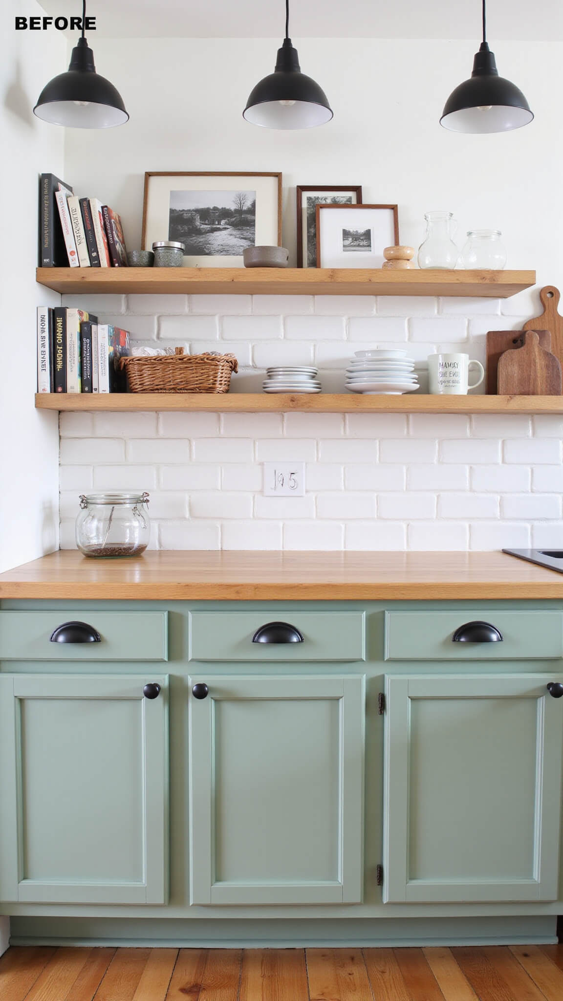 Sage green kitchen cabinets with matte black hardware, open shelving with decor, white subway tile backsplash, natural wood countertops, and budget pendant lights in a well-lit, straight-on view.